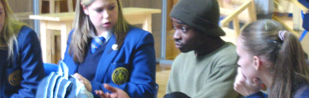 A photograph taken at a previous Arc Theatre workshop: a group of pupils seated in a circle listening to a facilitator. 