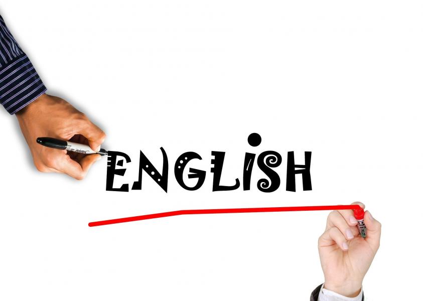 A photoshopped image of one hand writing &#039;English&#039; in black ink and another hand underlining it with red ink.