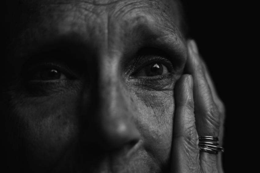 A close up black and white photo of an elderly person looking distressed.