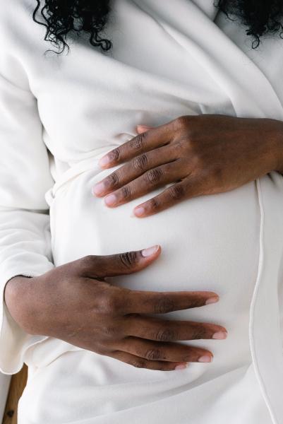 A photograph of a pregnant woman holding her abdomen. 