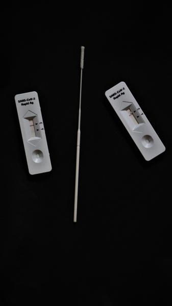 A photograph of two LFDs and a swab against a black background. 