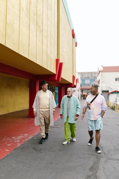 A group of three older people walking and talking together in a city.