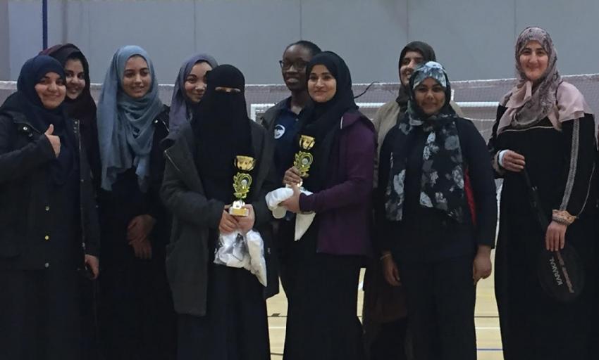 Women, some in hijab, hold a trophy